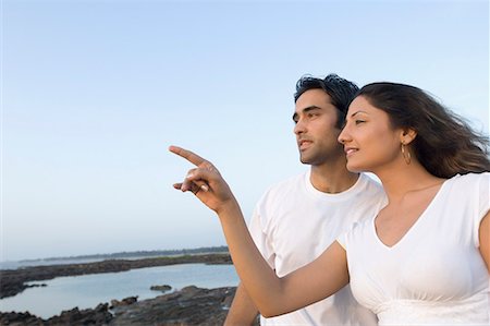 pointing horizon - Side profile of a young woman pointing forwards with a young man standing beside her, Madh Island, Mumbai, Maharashtra, Stock Photo - Premium Royalty-Free, Code: 630-01708672
