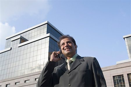 Low angle view of a businessman talking on a mobile phone and smiling Stock Photo - Premium Royalty-Free, Code: 630-01708688