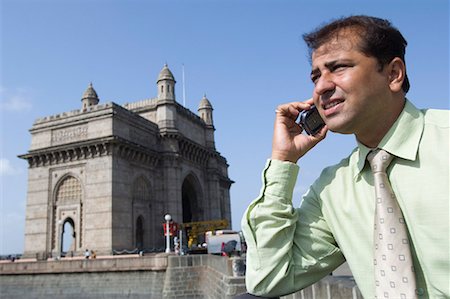 simsearch:630-01708665,k - Close-up of a businessman talking on a mobile phone with a monument in the background, Gateway of India, Mumbai, Maharashtra, India Stock Photo - Premium Royalty-Free, Code: 630-01708703