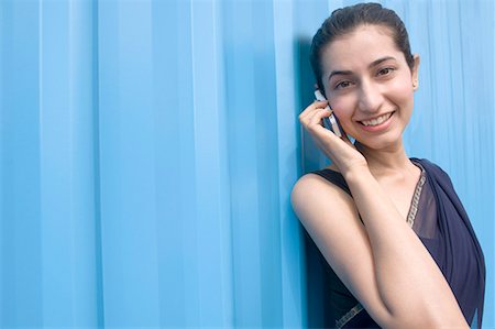 Portrait of a young woman talking on a mobile phone and smiling Stock Photo - Premium Royalty-Free, Code: 630-01708756