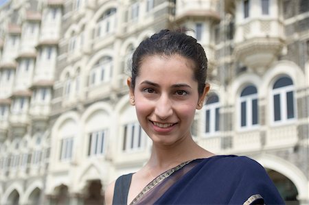 simsearch:630-01872968,k - Porträt einer jungen Frau lächelnd mit einem Hotel im Hintergrund, Taj Mahal Palace & Tower, Colaba, Indien Stockbilder - Premium RF Lizenzfrei, Bildnummer: 630-01708758