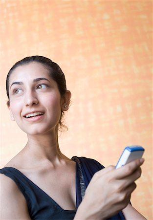 Close-up of a young woman holding a mobile phone and smiling Stock Photo - Premium Royalty-Free, Code: 630-01708773