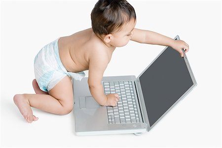 High angle view of a baby girl playing with a laptop Foto de stock - Sin royalties Premium, Código: 630-01709098