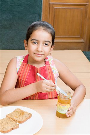 Portrait of a girl putting a table knife into a jam jar Stock Photo - Premium Royalty-Free, Code: 630-01709127