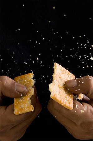 Close-up of a person's hand breaking a biscuit Stock Photo - Premium Royalty-Free, Code: 630-01709524