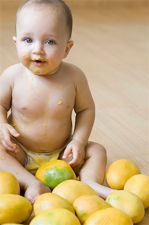 Portrait of a baby sitting on the hardwood floor and getting messy with mangoes Stock Photo - Premium Royalty-Free, Code: 630-01709602