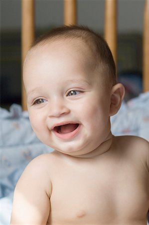 Close-up of a baby boy sitting in a crib and smiling Stock Photo - Premium Royalty-Free, Code: 630-01709612