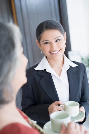 simsearch:630-01874002,k - Close-up of two businesswomen holding cups of tea and smiling Stock Photo - Premium Royalty-Free, Code: 630-01874036