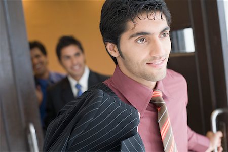 simsearch:630-01873857,k - Close-up of a businessman moving out from a conference room with his colleagues standing in the background Foto de stock - Royalty Free Premium, Número: 630-01874059