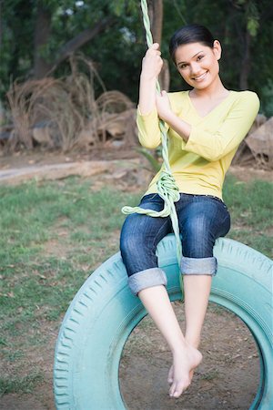 rolled up - Portrait d'une jeune femme se balancer sur une balançoire pneu Photographie de stock - Premium Libres de Droits, Code: 630-01874214