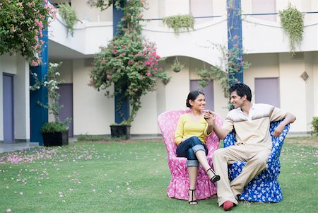 sitting holding legs up - Young couple sitting in a lawn and smiling Stock Photo - Premium Royalty-Free, Code: 630-01874250