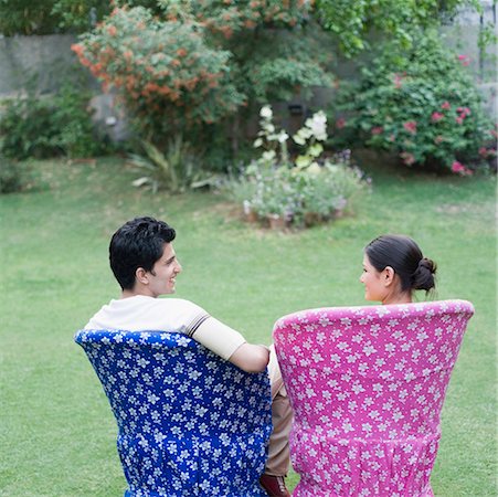 Rear view of a young couple sitting on chairs in a lawn Stock Photo - Premium Royalty-Free, Code: 630-01874251