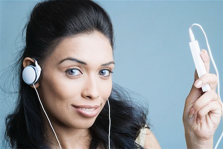 Portrait d'une jeune femme à l'écoute d'un lecteur MP3 et souriant Photographie de stock - Premium Libres de Droits, Code: 630-01874406
