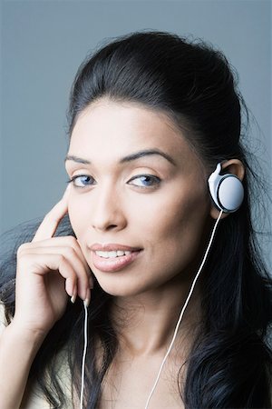 Portrait of a young woman listening to an MP3 player and smiling Stock Photo - Premium Royalty-Free, Code: 630-01874401