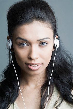 Portrait of a young woman listening to headphones and smiling Stock Photo - Premium Royalty-Free, Code: 630-01874402