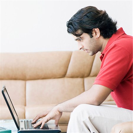 Side profile of a young man working on a laptop Stock Photo - Premium Royalty-Free, Code: 630-01874603