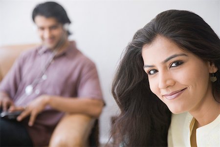 simsearch:630-01708665,k - Portrait of a young woman smiling with a young man sitting in the background Stock Photo - Premium Royalty-Free, Code: 630-01874648