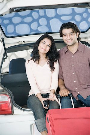 Portrait of a young couple sitting in a car trunk and smiling Stock Photo - Premium Royalty-Free, Code: 630-01874783