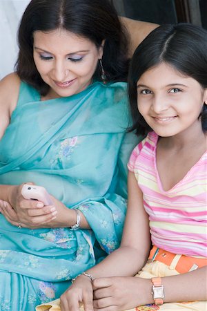 Mature woman using a mobile phone with her daughter smiling beside her Stock Photo - Premium Royalty-Free, Code: 630-01874811