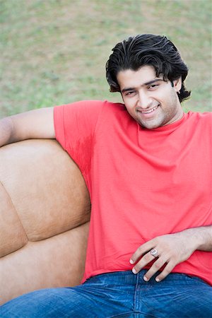 Portrait of a young man sitting in an armchair and smiling Stock Photo - Premium Royalty-Free, Code: 630-01874884
