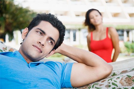 Close-up of a young man lying in a hammock with a young woman behind him Stock Photo - Premium Royalty-Free, Code: 630-01875069