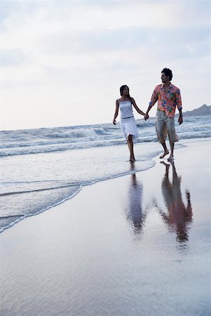 Young couple holding each other's hands and walking on the beach Foto de stock - Sin royalties Premium, Código: 630-01875172