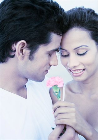Gros plan d'un jeune couple tenant une fleur et souriant Photographie de stock - Premium Libres de Droits, Code: 630-01875206