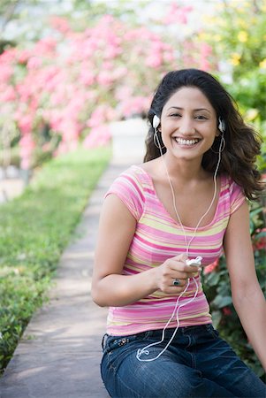 Portrait d'une jeune femme, écouter de la musique avec un lecteur Mp3 et souriant Photographie de stock - Premium Libres de Droits, Code: 630-01875258