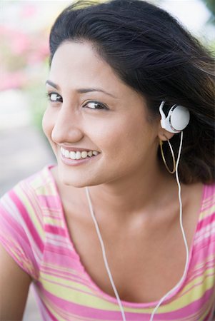 simsearch:630-01129601,k - Portrait of a young woman listening to music with an Mp3 player and smiling Foto de stock - Royalty Free Premium, Número: 630-01875261