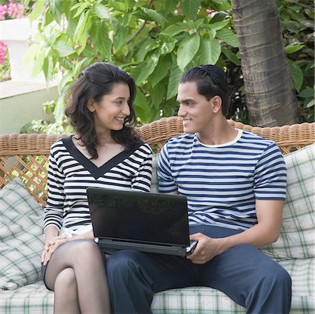 simsearch:630-01874586,k - Young couple sitting with a laptop on a couch and looking at each other Stock Photo - Premium Royalty-Free, Code: 630-01875289