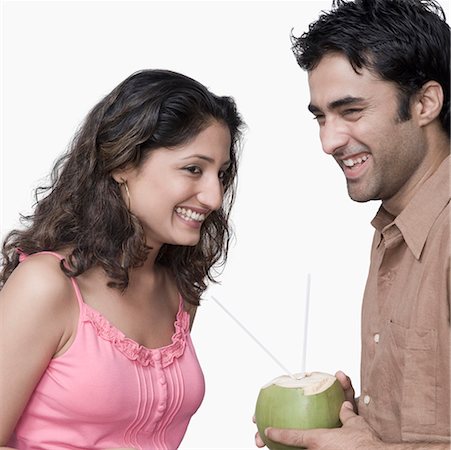 simsearch:630-01873358,k - Side profile of a young couple holding coconut milk and smiling Stock Photo - Premium Royalty-Free, Code: 630-01875352