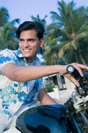 Young man sitting on a motorcycle and smiling Stock Photo - Premium Royalty-Free, Code: 630-01875460