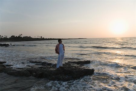 Young man standing on the coast with his hands in his pockets Stock Photo - Premium Royalty-Free, Code: 630-01875477