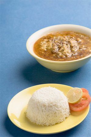 Close-up of a plate of rice with a bowl of curry Stock Photo - Premium Royalty-Free, Code: 630-01875651