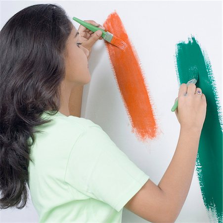 Side profile of a young woman painting the Indian flag on a wall Stock Photo - Premium Royalty-Free, Code: 630-01875894