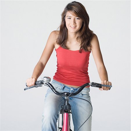 Portrait of a young woman riding a bicycle and smiling Stock Photo - Premium Royalty-Free, Code: 630-01876170