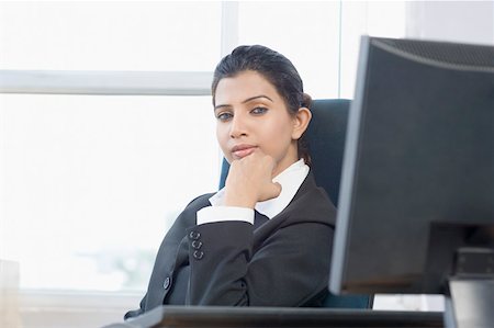 Portrait d'une femme d'affaires assis avec sa main sur son menton dans un bureau Photographie de stock - Premium Libres de Droits, Code: 630-01876360