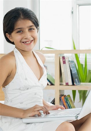 simsearch:630-01876447,k - Portrait of a girl using a laptop and smiling Foto de stock - Royalty Free Premium, Número: 630-01876427