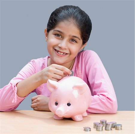 simsearch:630-01876449,k - Portrait d'une jeune fille de mettre une pièce de monnaie dans une tirelire et souriant Photographie de stock - Premium Libres de Droits, Code: 630-01876436