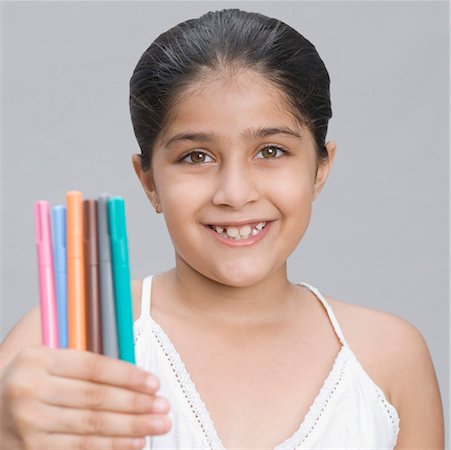 simsearch:630-01876449,k - Portrait d'une jeune fille tenant stylos et souriant Photographie de stock - Premium Libres de Droits, Code: 630-01876451