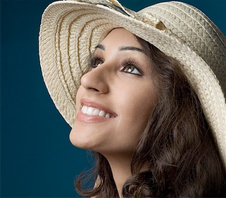 Close-up of a young woman wearing a straw hat and smiling Stock Photo - Premium Royalty-Free, Code: 630-01876470