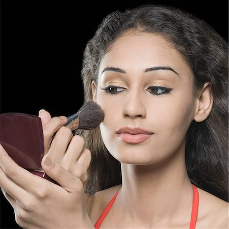 Close-up of a young woman applying blush on her face Stock Photo - Premium Royalty-Free, Code: 630-01876557