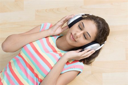 High angle view of a young woman lying on the hardwood floor and listening to music Stock Photo - Premium Royalty-Free, Code: 630-01876629