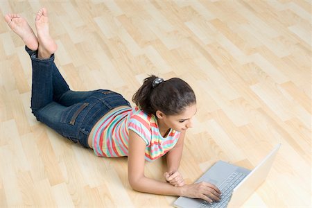 soles and feet and woman - High angle view of a young woman lying on the floor and using a laptop Stock Photo - Premium Royalty-Free, Code: 630-01876622