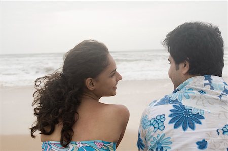 Rear view of a young couple sitting on the beach and smiling Stock Photo - Premium Royalty-Free, Code: 630-01876824