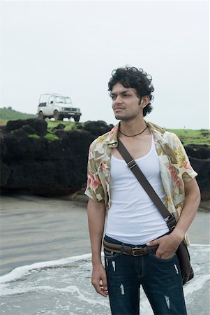 Young man standing on the beach with his jeep in the background Stock Photo - Premium Royalty-Free, Code: 630-01876852