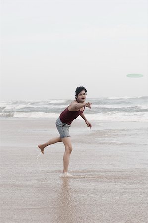 simsearch:630-01877039,k - Young man playing with a plastic disc on the beach Fotografie stock - Premium Royalty-Free, Codice: 630-01876915