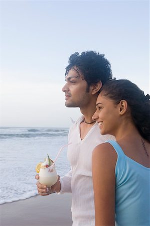 simsearch:630-01876927,k - Young woman standing with a young man holding a glass of cocktail on the beach Stock Photo - Premium Royalty-Free, Code: 630-01876924