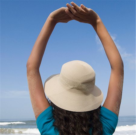 Rear view of a young woman standing with her arms raised on the beach Stock Photo - Premium Royalty-Free, Code: 630-01876967