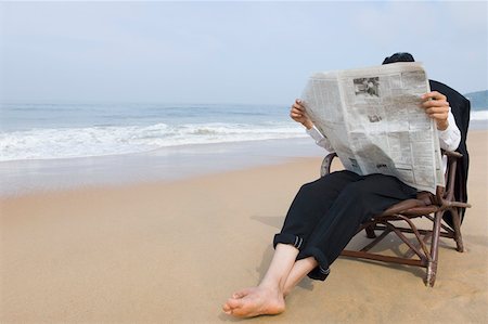 Businessman sitting in an armchair and reading a newspaper on the beach Stock Photo - Premium Royalty-Free, Code: 630-01877054